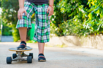 kid wearing green plaid pants on surfskate or Skateboard ready for riding at outdoor on the road
