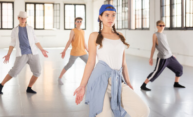 Fototapeta na wymiar Teenage girl practicing hip hop moves with friends at group dance class