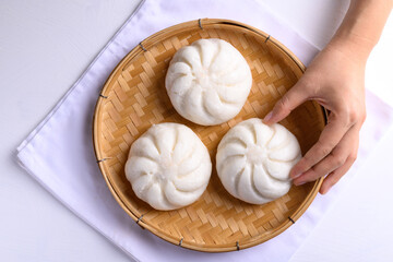 Steamed bun stuffed with minced pork on bamboo basket with hand, Asian food