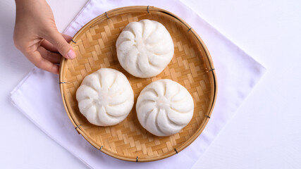 Steamed bun stuffed with minced pork on bamboo basket with hand, Asian food