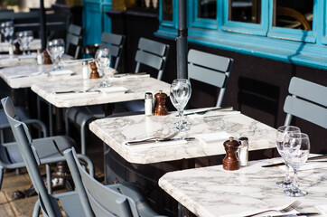 Set cafe tables on a sidewalk in Paris, France.