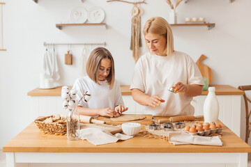 Mother and little daughter bake cookies and have fun in the kitchen. Homemade food. Happy loving family are preparing cookies together. Happy childhood