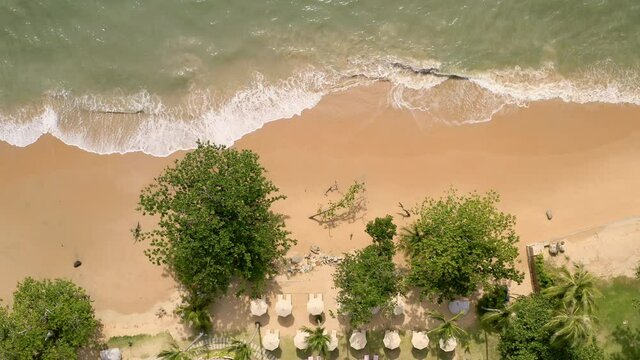 Relaxing sea waves on a hotel beach. Aerial view of small ocean waves on a paradise sand beach near big blue pool. Sea waves create vacation mood. People relax travel vacation fun concept.