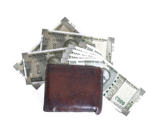Brown leather wallet with scattered Indian 500 rupee bills around it on an isolated white background © Arun Kumar/Wirestock