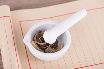 The white medicinal mortar with Pueraria lobata root on the blank notebook