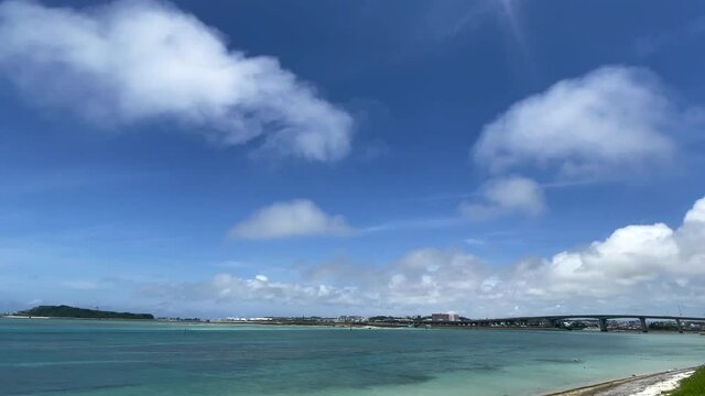 OKINAWA, JAPAN - JUNE 2021 : View of Senaga island and beach (Ocean or sea). Clear blue summer sky and clouds. Wide view time lapse shot in daytime.