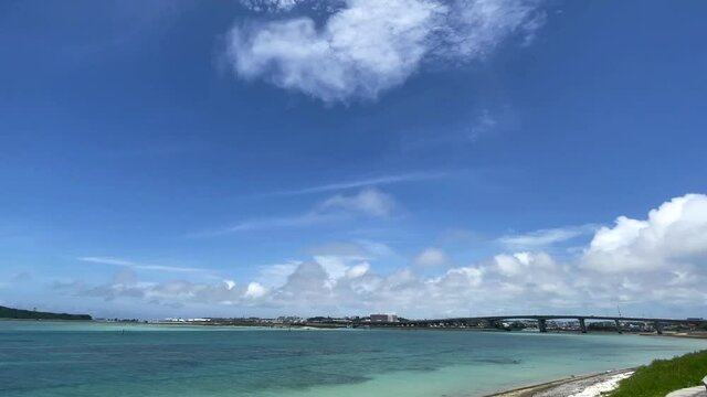 OKINAWA, JAPAN - JUNE 2021 : View of Senaga island and beach (Ocean or sea). Clear blue summer sky and clouds. Wide view time lapse shot in daytime.
