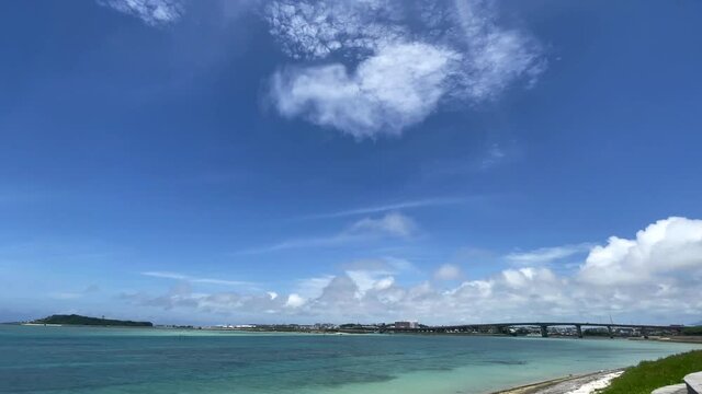 OKINAWA, JAPAN - JUNE 2021 : View of Senaga island and beach (Ocean or sea). Clear blue summer sky and clouds. Wide view time lapse shot in daytime.