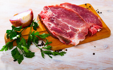 Fresh raw pork chop steak on wooden background with herbs
