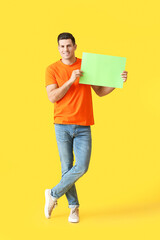 Young man with blank paper sheet on color background