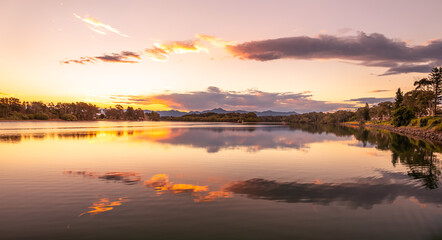 Fototapeta na wymiar Landscape spectacular golden reflections of the clouds and sunset in the beautiful, calm waters of a broad river in eastern Australia.