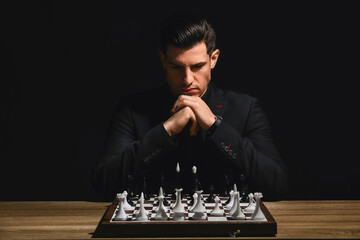 Man playing chess at table on dark background