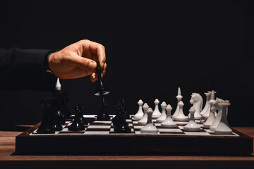 Man playing chess at table on dark background, closeup