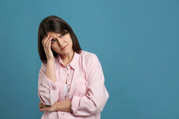 Young woman suffering from migraine on light blue background. Space for text