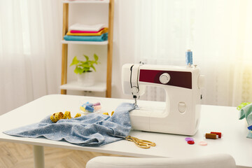 Modern sewing machine, fabric and accessories on table indoors, space for text