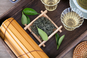 Green tea leaves on tray in wooden tea tray