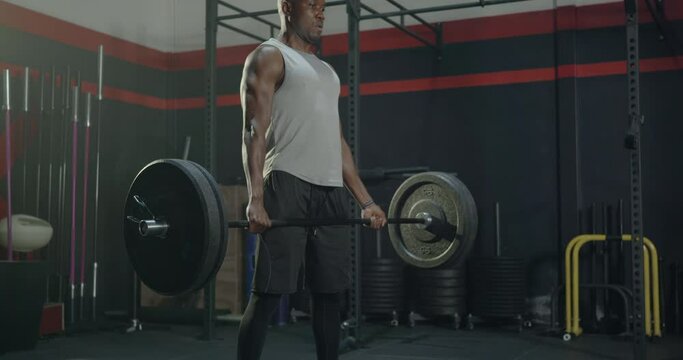 Muscular young black man exercises working out with lifting weights heavy barbell, Male bodybuilder having workout in gym and fitness club during alone training