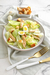 Plate with tasty Caesar salad on light background