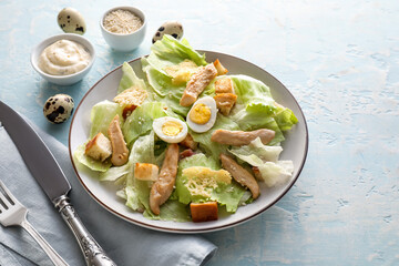 Plate with tasty Caesar salad and sauce on color background