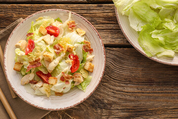 Plate with tasty Caesar salad on wooden background