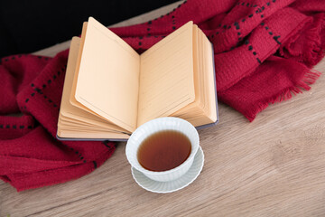 A bowl of tea and an open book and scarf