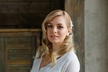 Fototapeta premium Boudoir photo of the bride in the morning. A beautiful portrait of a young blonde woman in a white coat sitting by the window.