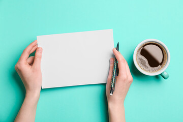 Female hands with blank sheet of paper, pencil and cup of coffee on color background