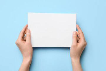 Woman holding blank sheet of paper on color background, closeup