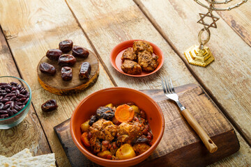 Jewish dish shuttle with meat in a dish on a wooden table next to matzo. Fork and ingredients.