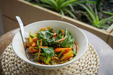 Chinese kale fried in oyster sauce and served in a bowl on the table.