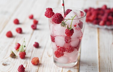 A glass of tonic with raspberries and ice. Quench your thirst in hot summer.