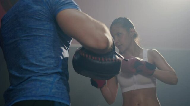 Asian beautiful young woman exercise with trainer at boxing gloves and self defense lesson punching, Female kickboxing training with male Instructor fight at fitness GYM, workout healthy sport concept