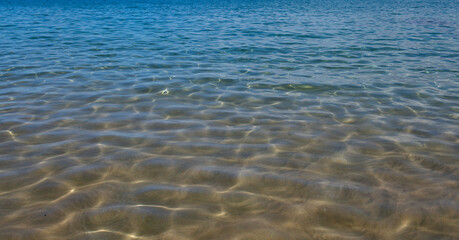 Calm sea water surface texture with splashes and waves. Abstract nature background. Background of aqua ocean water surface.