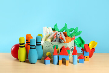 Many different toys on wooden table against light blue background