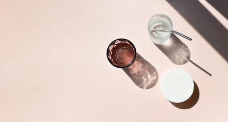 Summer sunlight still life mock up composition. Cocktail glass and round pedestal on beige background. Trendy eco minimalist concept for branding, vacation, relax. Harsh shadows. Top view, copy space