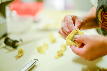 person making tortelli, traditional italian stuffed pasta,  in the kitchen