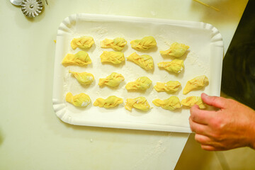 person making tortelli con la coda in the kitchen