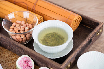 A bowl of green tea and a few rolls of bamboo slips in a tea tray