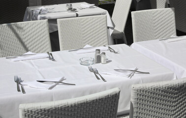 set table with white tablecloths and white chairs in the restaurants waiting for tourists