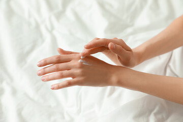 Woman applying hand cream in bed, closeup