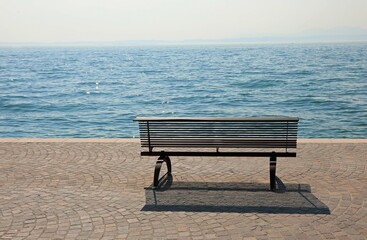 Naklejka na ściany i meble bench on the shore with the placid water symbol of tranquility and relaxation