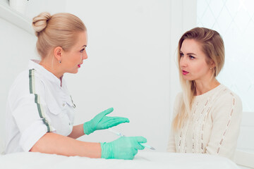 Young woman beautician talking with a young blond woman about new facial skin care procedures, Professional cosmetician examining face skin