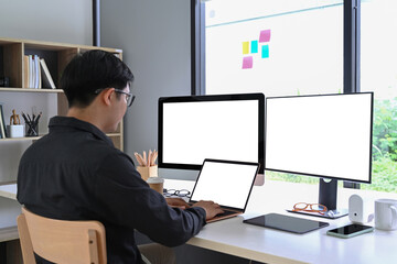 Back view of businessman working with multiple modern gadget at home office.