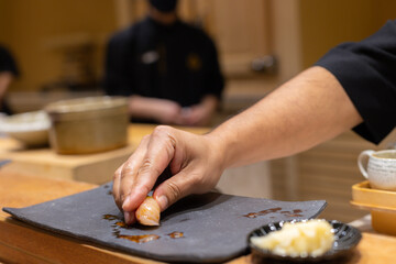 Close up of Japanese chef put the sushi into the plate. Omakase couse.