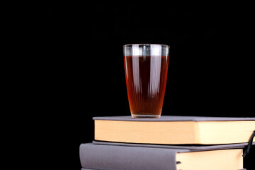 A cup of black tea on the book in front of black background