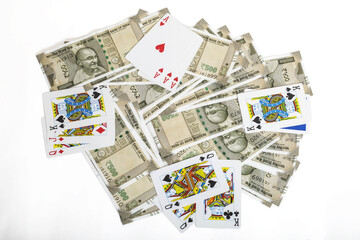 Top view of a pile of Indian rupees with playing cards on a white background