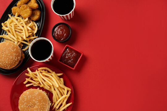 Different fast food on red background, flat lay. Space for text