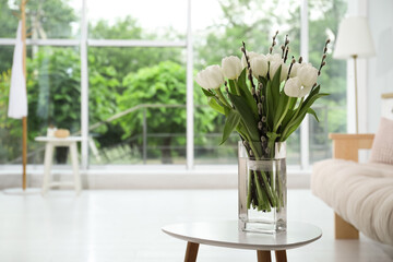 Beautiful bouquet of willow branches and tulips in vase on table indoors, space for text