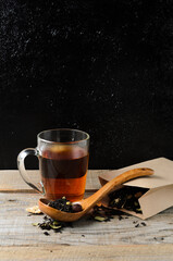 A glass mug of fragrant brewed flower tea on a wooden table, with a wooden spoon