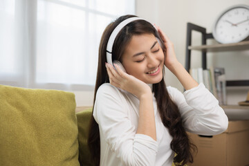 Relaxing time on sofa. Beautiful young asian woman lay down on sofa and listening to the music with headphone. She has rhythm Lifestyle in living room at house in the morning.